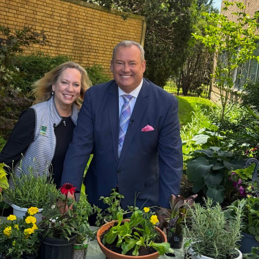 Sue Ryba of Bertog Landscape with the WGN Midday News anchor beside potted herbs and vegetables.